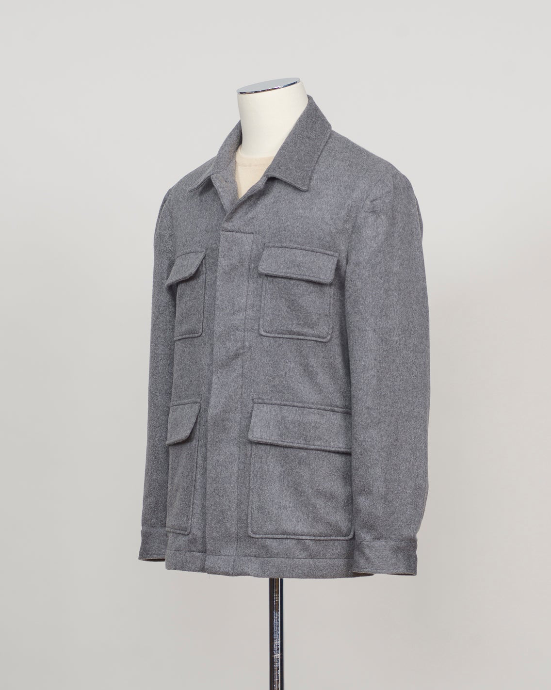 A gray textured utility jacket displayed on a mannequin torso against a light gray studio background.