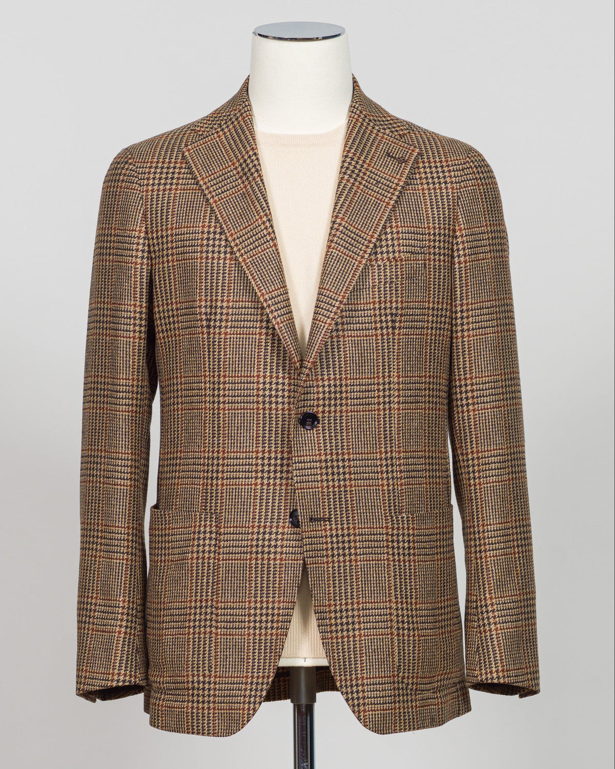 A men's single-breasted plaid blazer in brown and beige tones, displayed on a white mannequin torso against a light gray background. Classic Prince of Wales check blazer in rich brown tones. Tailored construction with refined detailing, perfect for elevating everyday wear or layering with knitwear. Italian craftsmanship meets timeless menswear design—an essential piece for the discerning wardrobe. Tagliatore Prince Of Wales Jacket / Brown