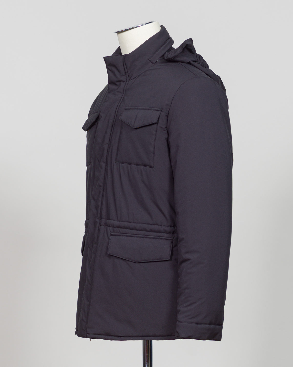 A dark navy blue quilted jacket displayed on a white mannequin torso against a neutral light gray The Gran Sasso Padded Nylon Jacket in navy delivers genuine warmth without the weight. Its lightweight thermowadding construction and refined collar offer understated sophistication—equally at home over a dress shirt or layered with knitwear. Italian craftsmanship meets everyday practicality: polished for client meetings, reliable for daily wear, and versatile enough to become your most trusted layerbackground.