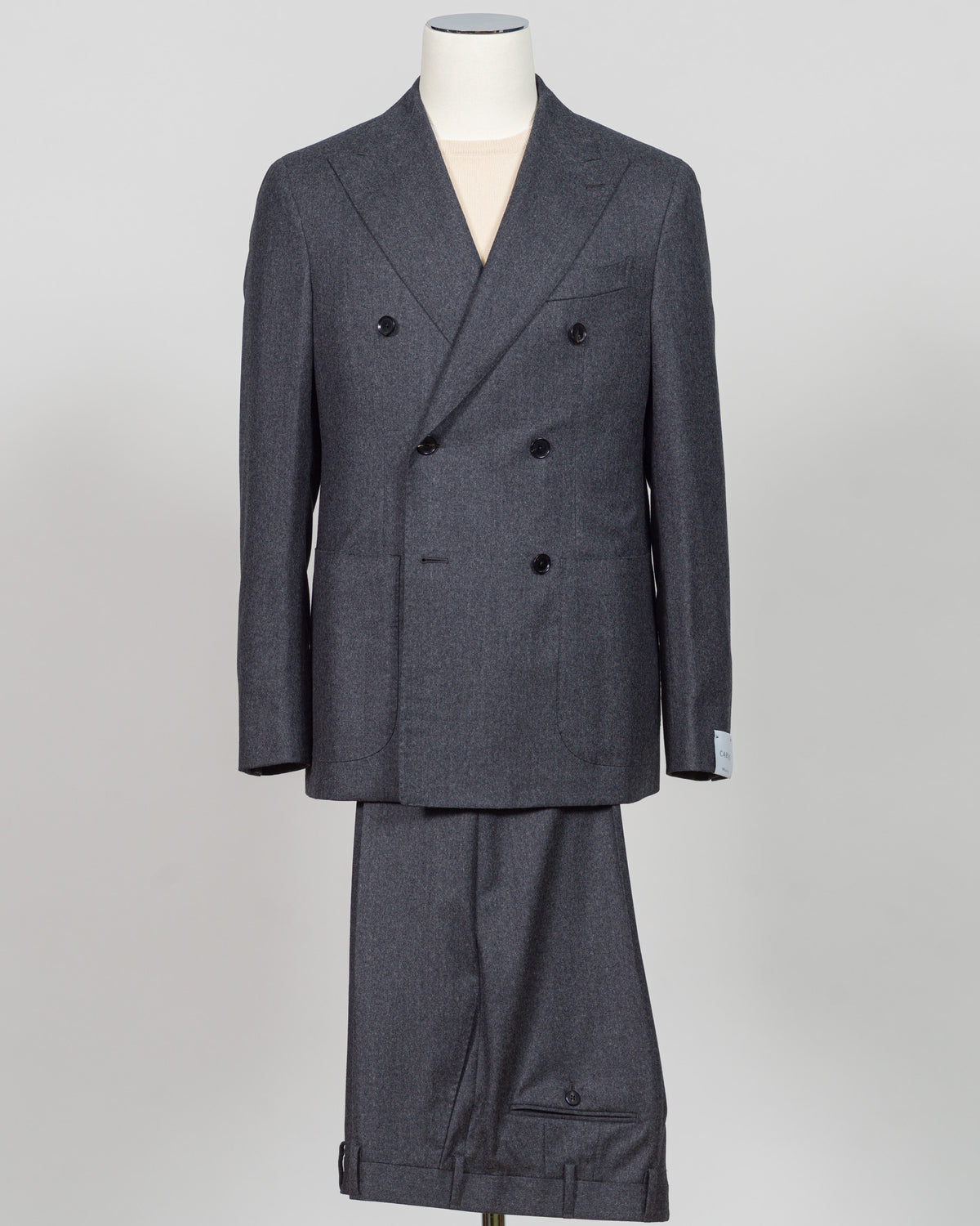 A dark gray double-breasted suit with a subtle micro-check pattern, displayed on a mannequin against a light gray background. Refined elegance in a timeless double-breasted silhouette. This Caruso suit pairs the warmth of quality flannel with sophisticated tailoring, delivering understated luxury suited to both boardroom and evening occasions. Dark grey ensures versatility across your wardrobe while the construction speaks to meticulous craftsmanship and enduring style.Caruso Double-Breasted Flannel Suit /