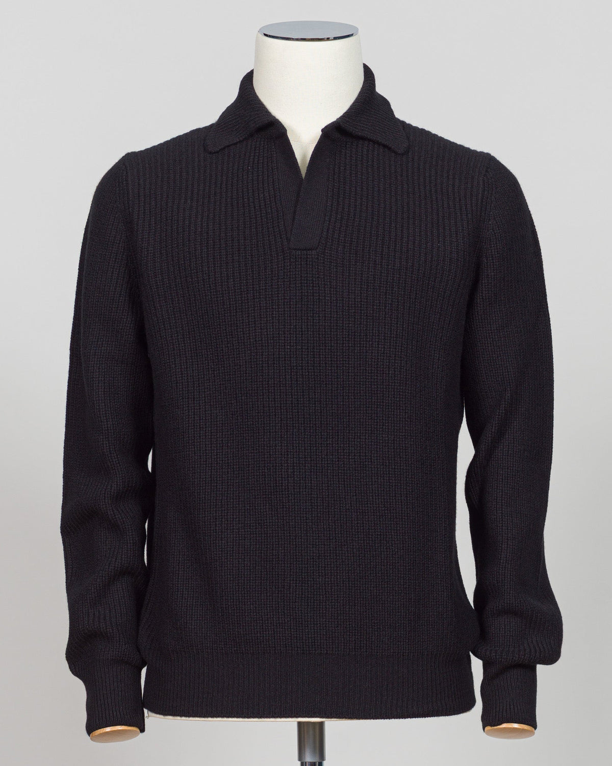 A black ribbed knit polo sweater displayed on a white mannequin torso against a light gray studio background. A refined essentials piece crafted from premium ribbed knit. The Gran Sasso polo delivers timeless elegance through its structured fabric and clean lines — perfect for layering or worn alone. Black colourway suits any wardrobe foundation. Gran Sasso Ribbed Polo / Black