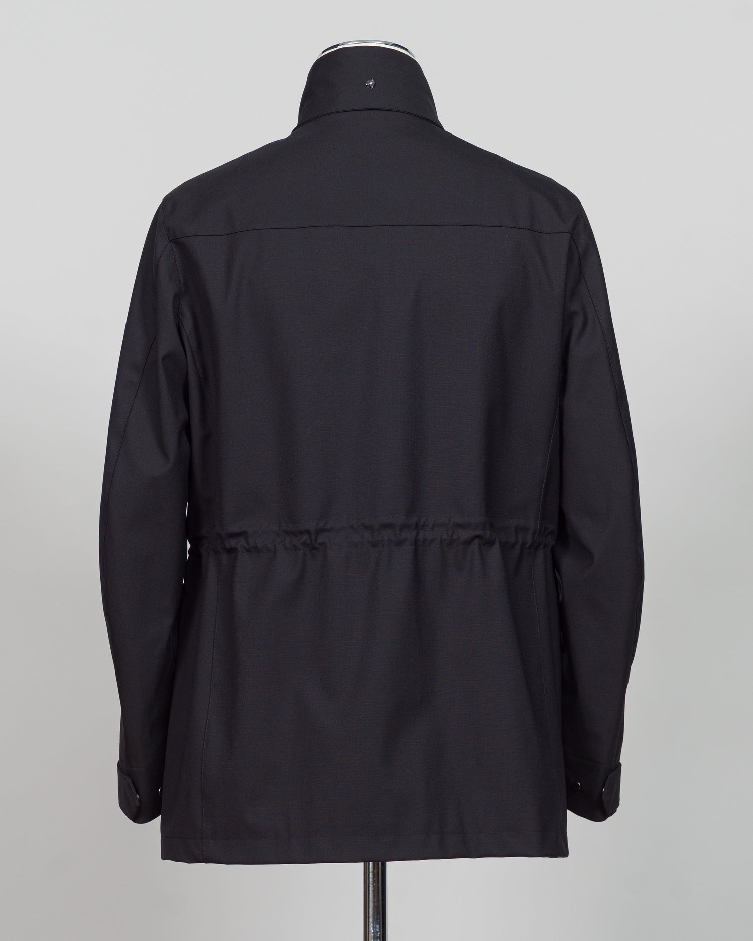 A black long-sleeve jacket with a high collar and a drawstring waist, shown from the back on a mannequin against a light gray background.