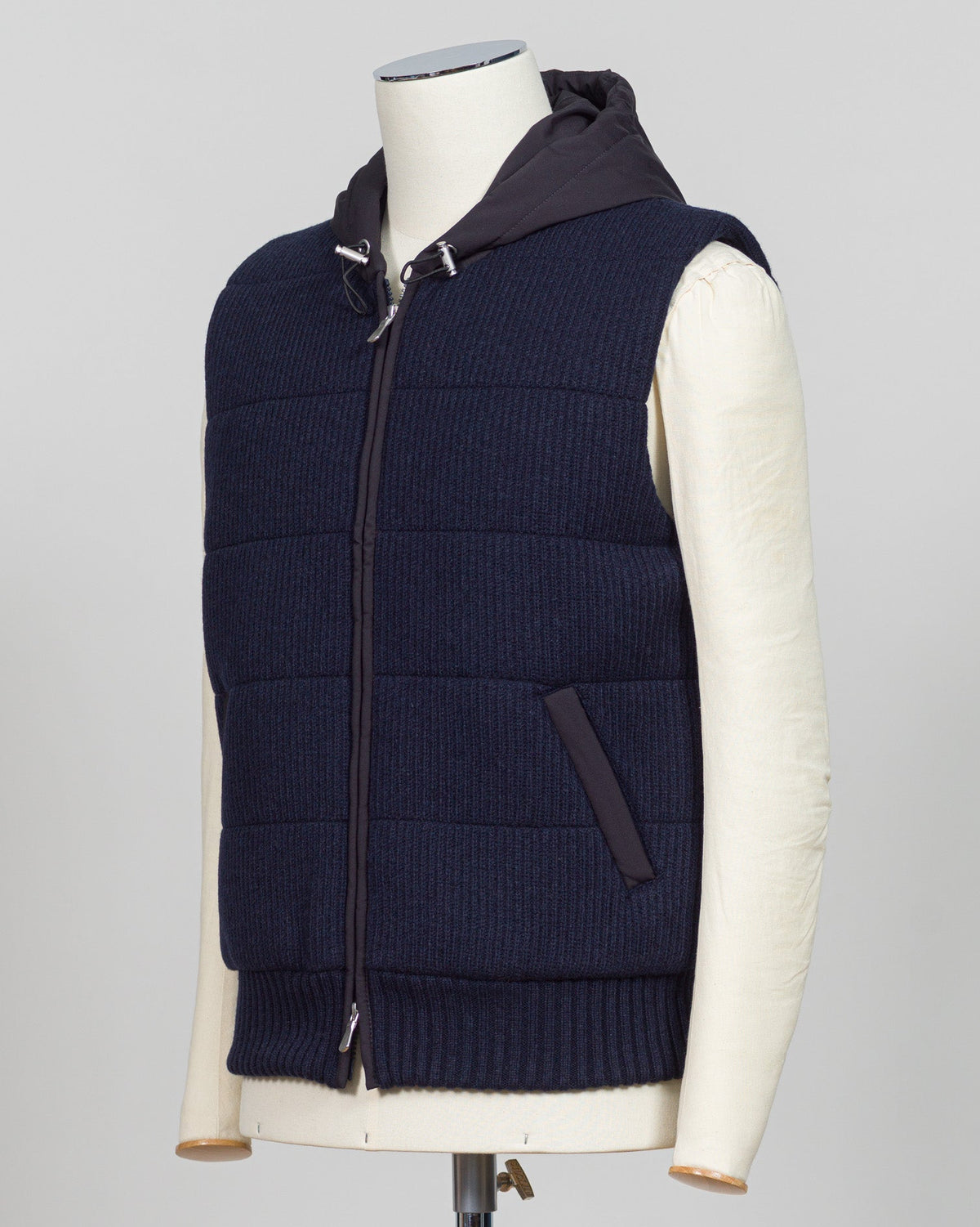 Lightweight padded hooded vest in deep navy. Crafted by Gran Sasso, this essential layer offers sophisticated warmth without bulk. Perfect layered over knitwear or worn standalone for refined, modern styling. Premium construction ensures lasting comfort and durability. Gran Sasso Padded Hooded Vest / Navy