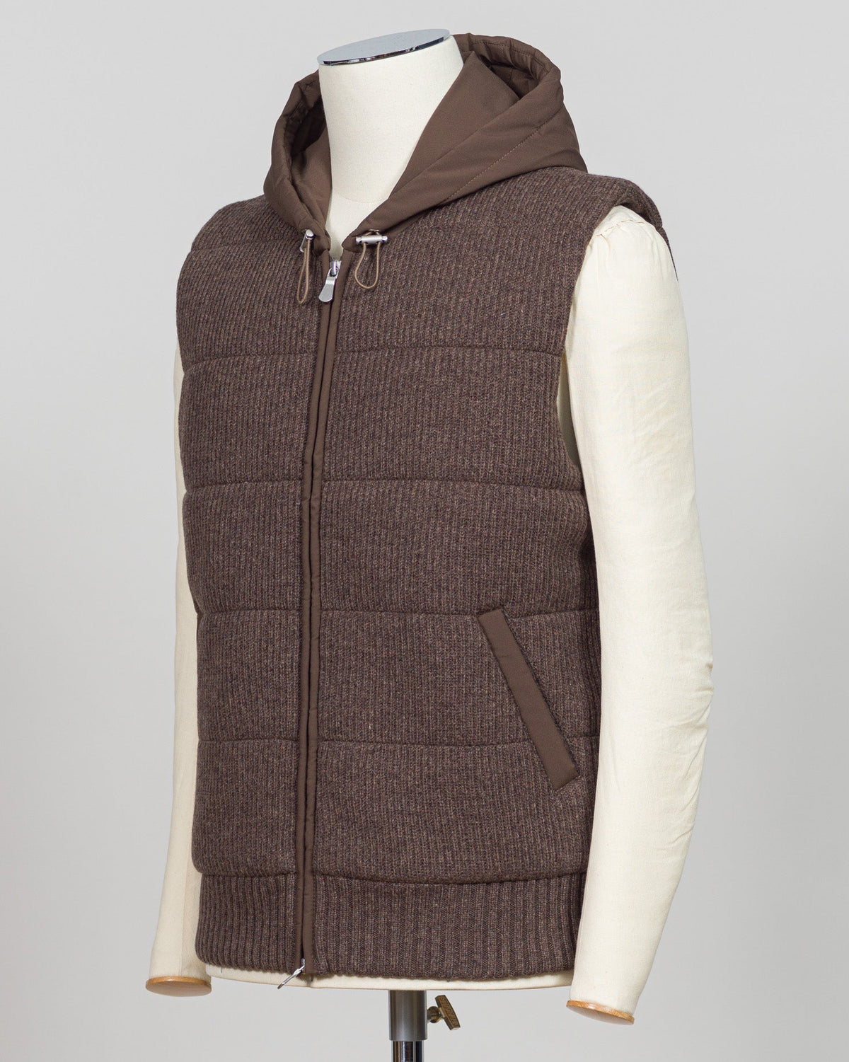 Lightweight padded hooded vest in rich brown, crafted by Italian luxury knitwear specialist Gran Sasso. Designed for layering over fine knits and tailored pieces, this vest offers warmth without bulk. The structured silhouette and refined proportions suit both casual and smart-casual styling. Perfect for transitional seasons and travel. Gran Sasso Padded Hooded Vest / Brown