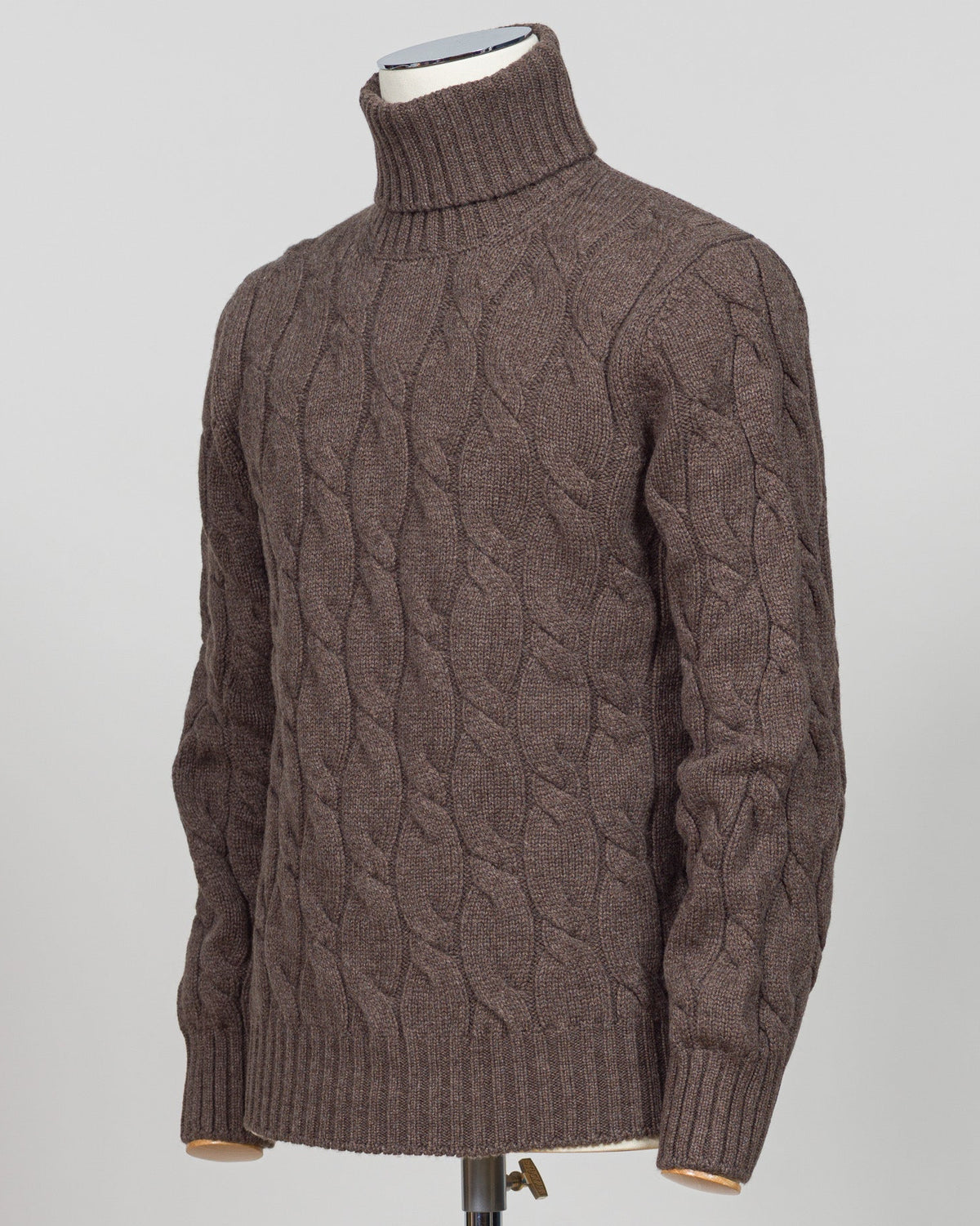 A brown cable-knit turtleneck sweater displayed on a mannequin torso against a light gray background. Italian wool cable knit roll neck in rich brown. Classic construction with texture and warmth, cut for refined layering under tailored jackets or worn as a standalone piece. Gran Sasso delivers understated luxury in heritage knitwear. Gran Sasso Cable Roll Neck Knit / Brown