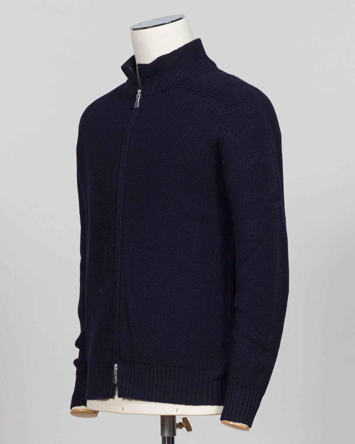 A dark navy blue ribbed knit zip-up sweater displayed on a white mannequin torso against a light gray Water-repellent merino wool hoodie in navy. Engineered for layering and everyday wear, this Gran Sasso piece combines breathable warmth with practical weather resistance. Perfect for transitional seasons and active lifestyles. Gran Sasso Rain Wool Hoodie / Navybackground.