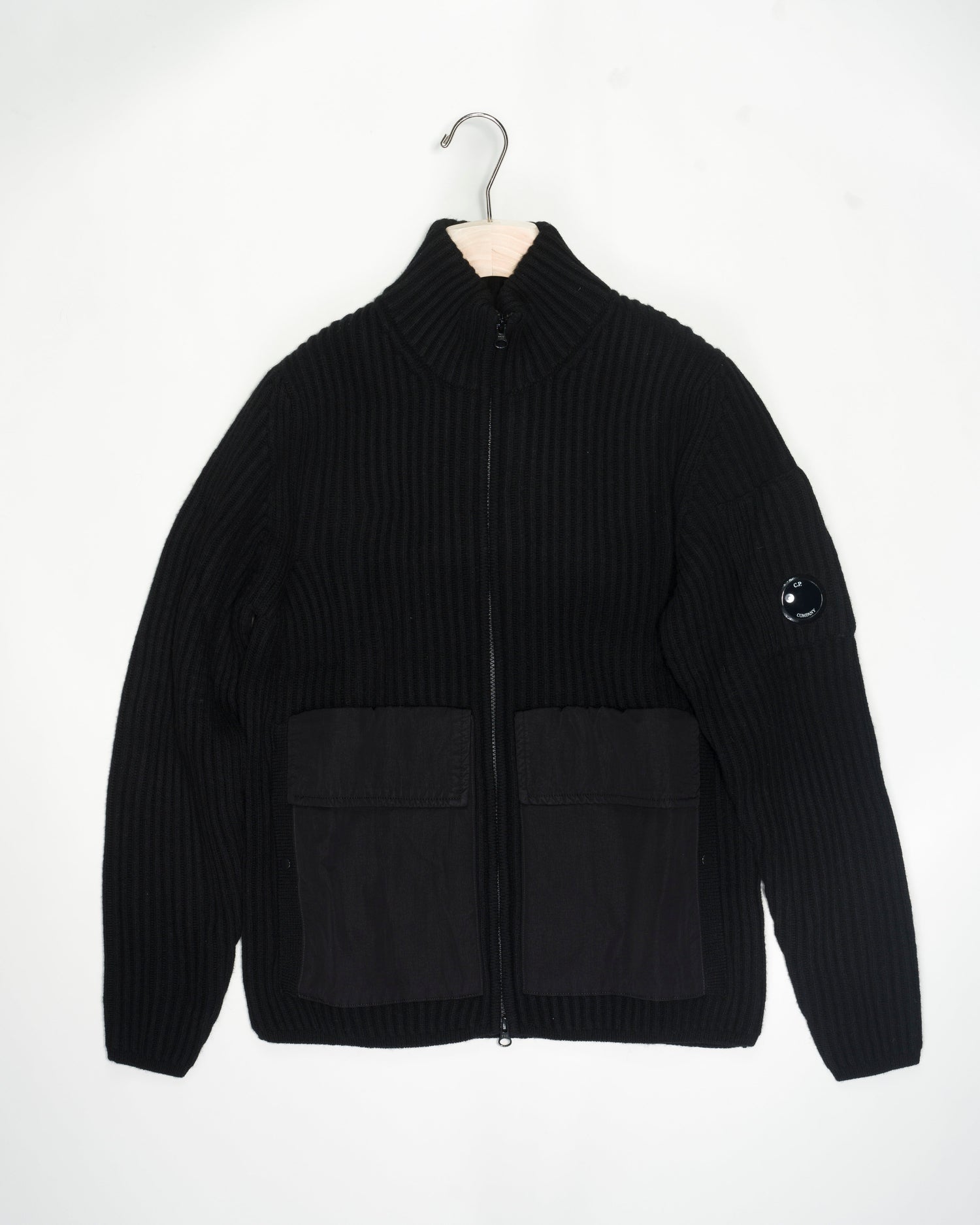 C.P. Company Lambswool Mixed Zipped Knit / Black 15CMKN226A 005504MG Col 999 Black 80% wool 20%polyamide 2 flapped nylon pockets and 2 hand warmer pockets with snap buttons 2 way zip in front