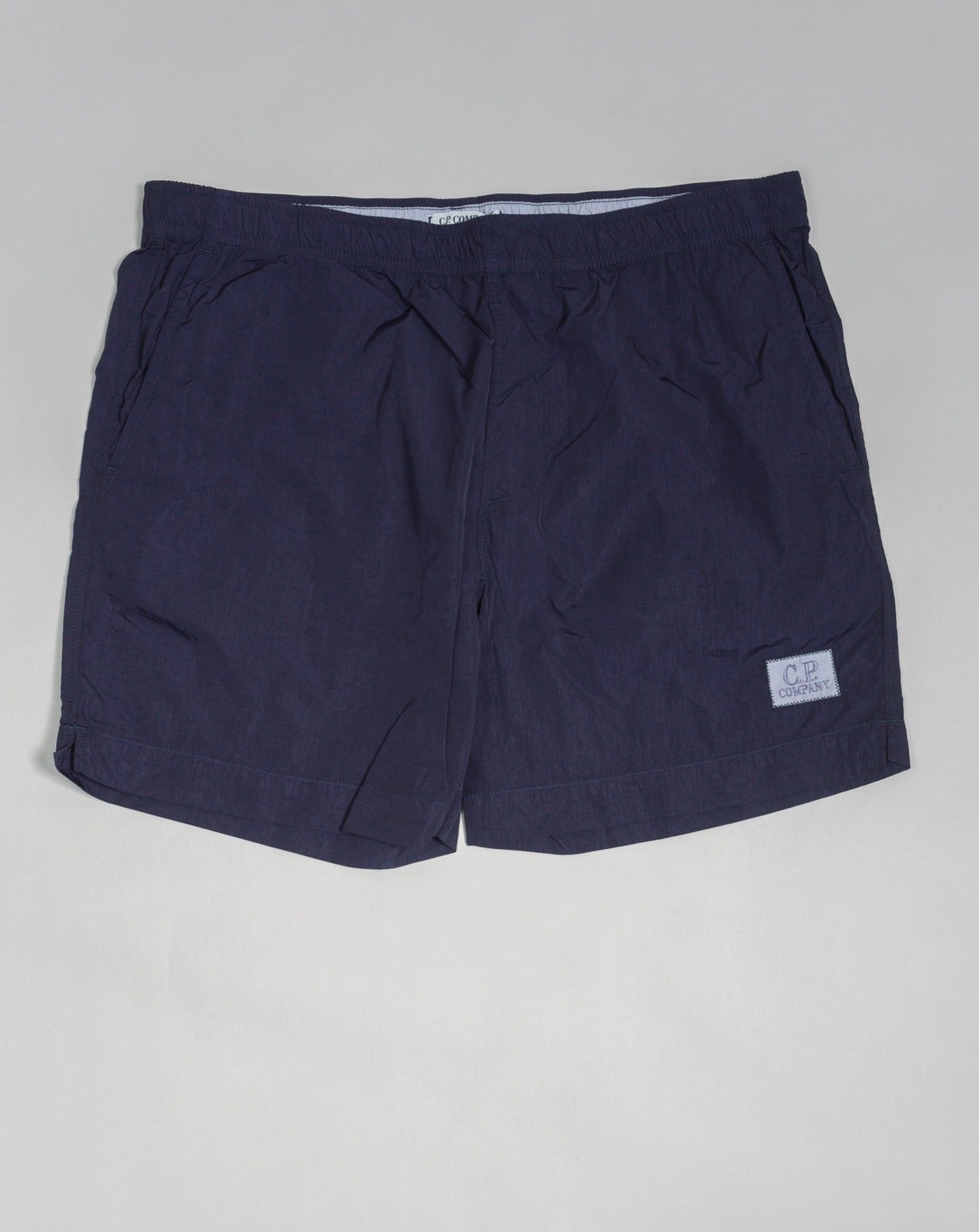 Eco-Chrome swim shorts constructed with an elasticated drawstring waist, hand pockets and a logo detail. Chrome is C.P. Company’s foundation woven multifilament nylon. This new version uses Econyl® regenerated nylon yarns, created through the upcycling of fishing nets. Art. BW005A 6369G Col. 868 Medieval Blue Elasticated drawstring waist Hand pockets Logo detail Nylon dyed