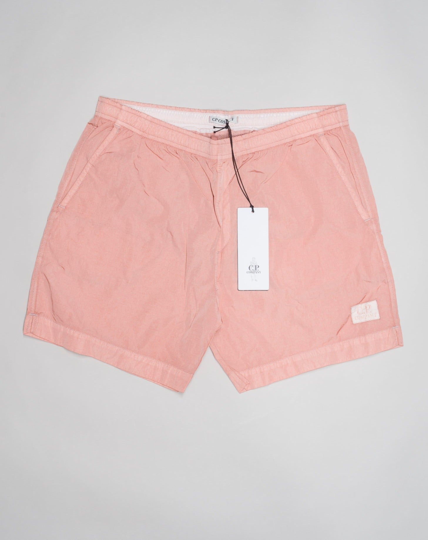 Eco-Chrome swim shorts constructed with an elasticated drawstring waist, hand pockets and a logo detail. Chrome is C.P. Company’s foundation woven multifilament nylon. This new version uses Econyl® regenerated nylon yarns, created through the upcycling of fishing nets. Art. BW005A 6369G Col. 509 Pale Mauve Elasticated drawstring waist Hand pockets Logo detail Nylon dyed