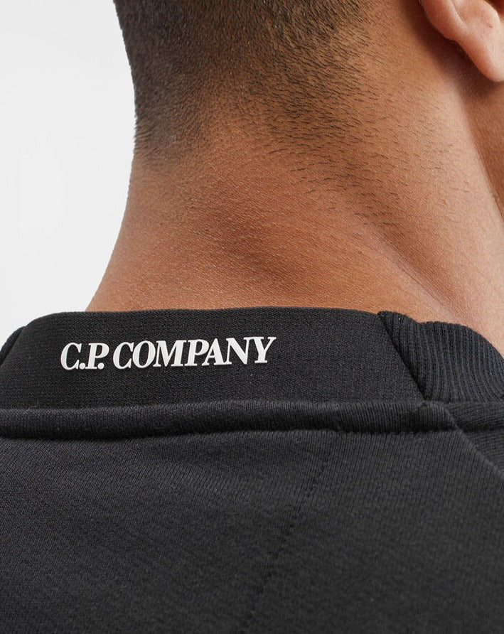 15CMSS022A 005086W Col 999 Black Crew Neck Loopback cotton 100% cotton Lens detailing on left arm zip pocket Logo detailing in back collar Ribbed hem and cuffs C.P. Company Diagonal Raised Fleece Lens Sweatshirt / Black