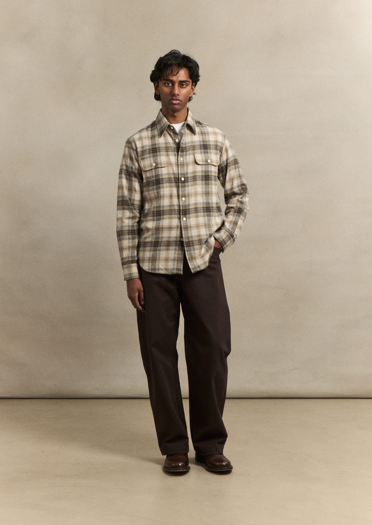 A refined artist's shirt in a subtle grey Camargue check, cut from premium cotton for effortless layering and everyday wear. The relaxed fit and considered proportions reflect De Bonne Facture's commitment to timeless, wearable design, structured enough to pair with tailored trousers or casual knitwear.