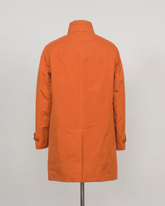 An orange mid-length coat displayed on a dress form mannequin, viewed from the back against a neutral light gray background.