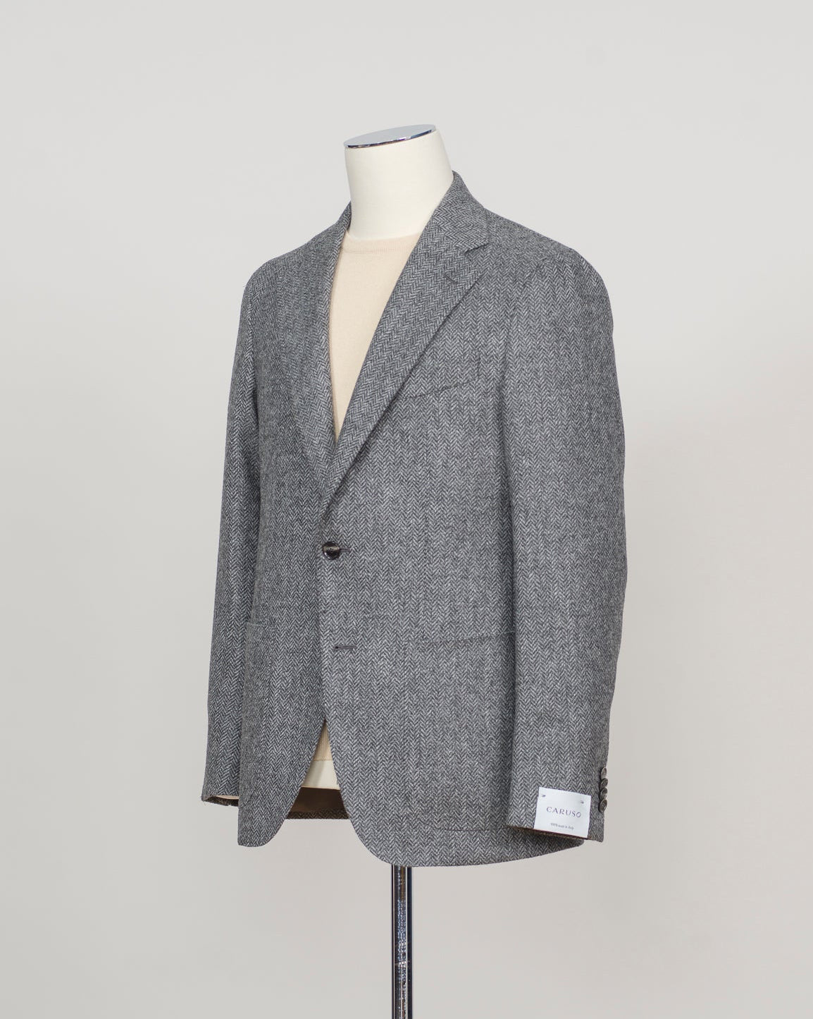 A gray textured blazer displayed on a cream-colored mannequin torso, set against a plain light gray background.