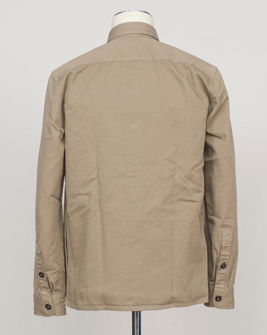 A beige long-sleeve utility jacket displayed on a mannequin torso, viewed from the back against a plain light gray background. Ghirardelli Heavy Twill Overshirt / Taupe Heavy twill overshirt in taupe. Crafted from substantial cotton twill for durability and structure. Classic overshirt silhouette layers effortlessly over knitwear or worn standalone. Designed for refined casual wear and everyday versatility.&nbsp;