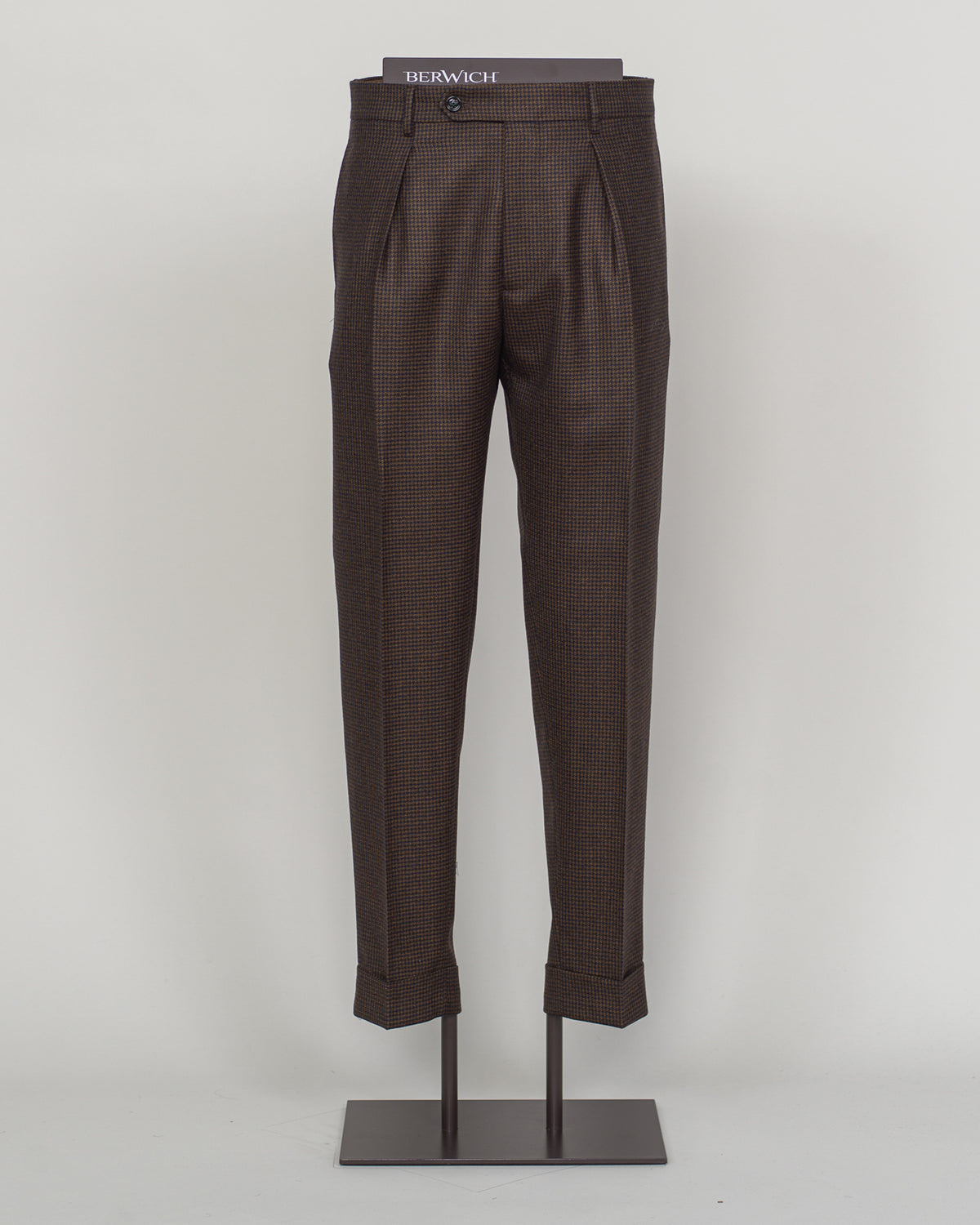 Berwich's Chiaia trousers showcase Italian tailoring heritage with a refined puppytooth pattern in brown. Cut with a contemporary silhouette and finished with precision pleating, these trousers balance classic structure with modern sophistication. The carefully selected fabric drapes with quiet elegance, making them an essential foundation for curated menswear wardrobes that demand both substance and understated style.