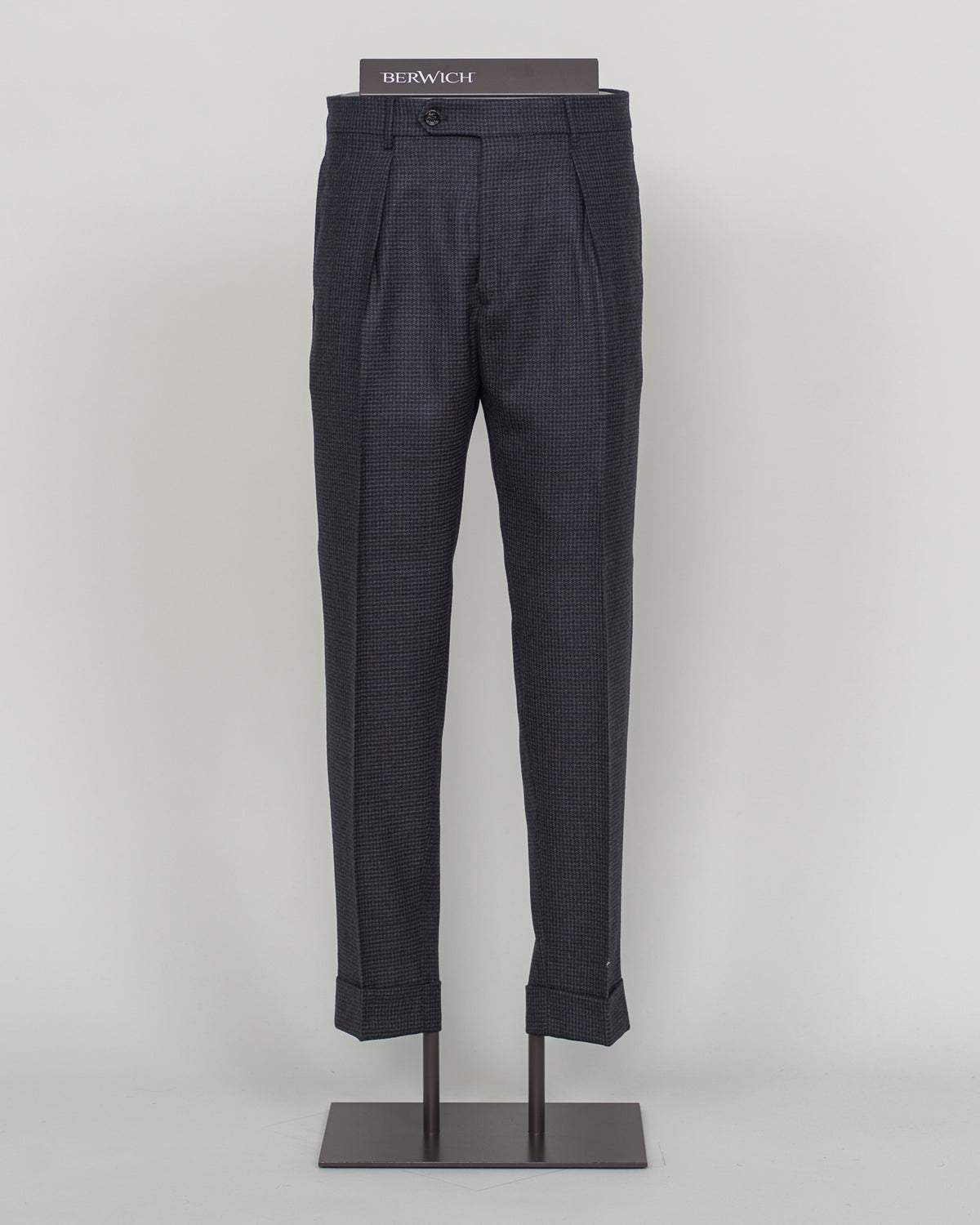 Berwich's Chiaia trousers showcase Italian tailoring heritage with a refined puppytooth pattern in dark navy. Cut with a contemporary silhouette and finished with precision pleating, these trousers balance classic structure with modern sophistication. The carefully selected fabric drapes with quiet elegance, making them an essential foundation for curated menswear wardrobes that demand both substance and understated style.