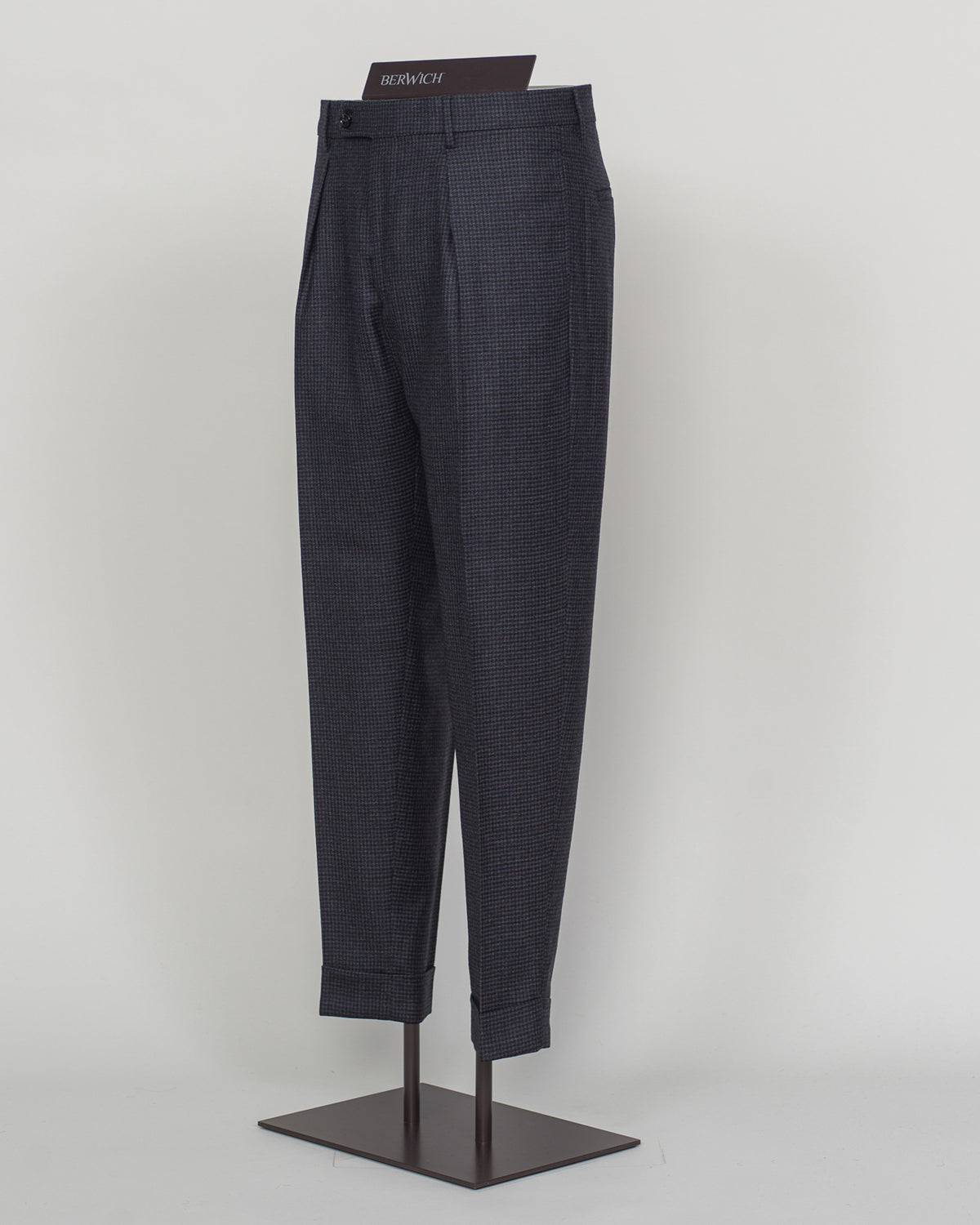 Berwich's Chiaia trousers showcase Italian tailoring heritage with a refined puppytooth pattern in dark navy. Cut with a contemporary silhouette and finished with precision pleating, these trousers balance classic structure with modern sophistication. The carefully selected fabric drapes with quiet elegance, making them an essential foundation for curated menswear wardrobes that demand both substance and understated style.