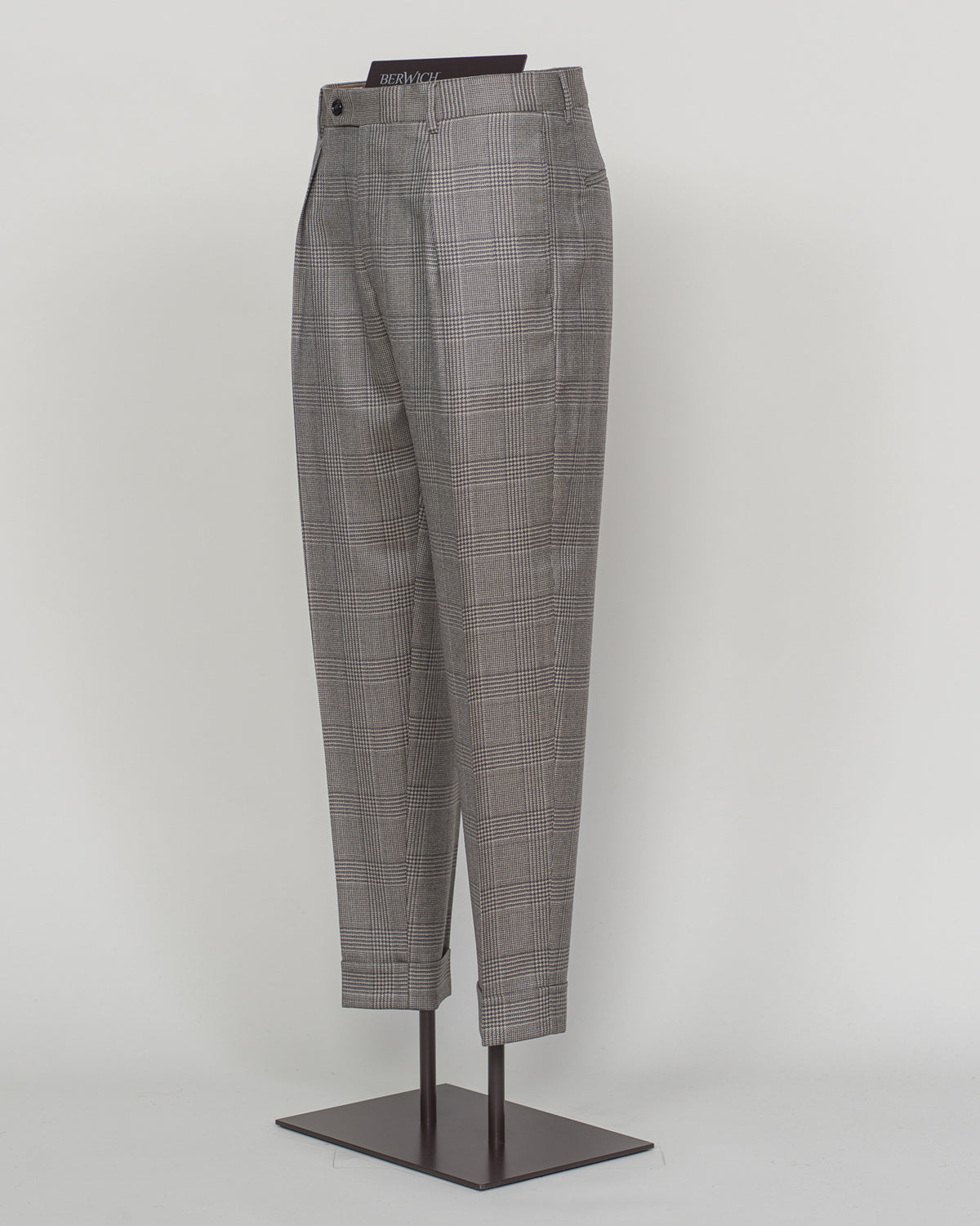 Berwich's Chiaia trousers showcase Italian tailoring heritage with a refined long glencheck pattern in warm greige. Cut with a contemporary silhouette and finished with precision pleating, these trousers balance classic structure with modern sophistication. The carefully selected fabric drapes with quiet elegance, making them an essential foundation for curated menswear wardrobes that demand both substance and understated style.