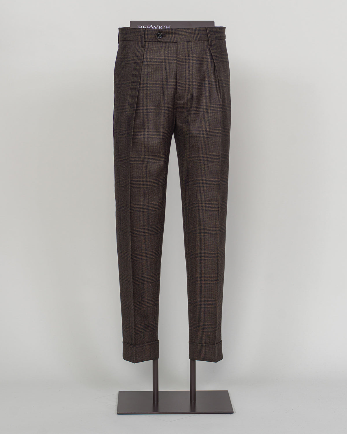 Pic 1 Berwich's Chiaia trousers showcase Italian tailoring heritage with a refined long glencheck pattern in warm brown. Cut with a contemporary silhouette and finished with precision pleating, these trousers balance classic structure with modern sophistication. The carefully selected fabric drapes with quiet elegance, making them an essential foundation for curated menswear wardrobes that demand both substance and understated style. Berwich Chiaia Long Glencheck Trousers / Brown