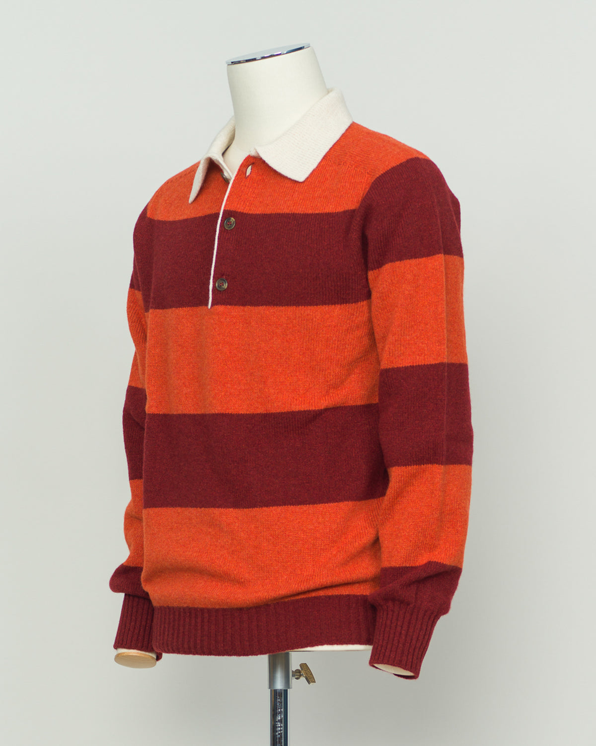 A timeless rugby polo crafted from pure wool, featuring Harley of Scotland's signature striped pattern in warm orange and red tones. The structured knit delivers excellent breathability and natural temperature regulation, ideal for layering or standalone wear. Classic collar and button placket with a relaxed yet refined fit that suits both casual and smart-casual settings. A versatile staple for the discerning wardrobe.