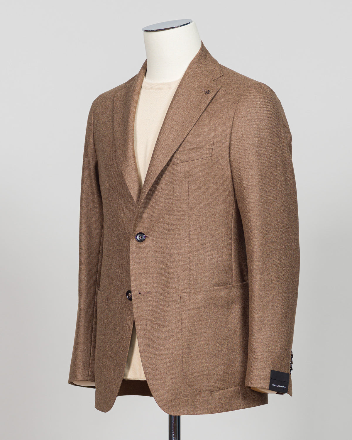 A brown tweed blazer displayed on a mannequin torso over a cream shirt, photographed against a light gray studio background. Refined tailoring meets supreme comfort in this Tagliatore sport jacket, crafted from 93% wool and 3% cashmere. The light brown tone offers versatile styling across seasons, while the luxurious blend delivers warmth without bulk. A wardrobe essential for the discerning gentleman seeking quality construction and understated elegance. Tagliatore Wool & Cashmere Jacket / Light Brown