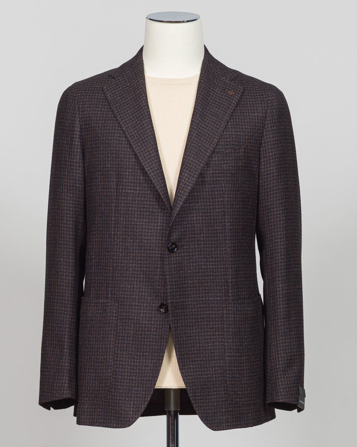 A dark brown and black micro-check patterned blazer jacket displayed on a white mannequin torso against a light gray background. Classic houndstooth sport jacket in rich dark brown. Italian tailoring with refined construction and timeless pattern versatility. Perfect for layering or as a standalone piece for business and weekend wear. Tagliatore Houndstooth Jacket / Dark Brown