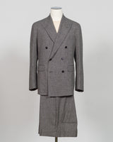 A gray double-breasted suit with a matching skirt, displayed on a mannequin against a light gray background. Tagliatore's double-breasted silhouette merges Italian craftsmanship with refined restraint. The brown and grey palette offers versatility across seasons and occasions—from boardroom formality to sophisticated evening wear. Carefully finished details and structured shoulders create a commanding presence while maintaining contemporary proportion. Cut for the discerning wearer who values timeless tailo