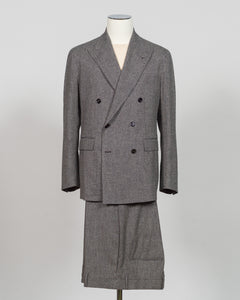 A gray double-breasted suit with a matching skirt, displayed on a mannequin against a light gray background. Tagliatore's double-breasted silhouette merges Italian craftsmanship with refined restraint. The brown and grey palette offers versatility across seasons and occasions—from boardroom formality to sophisticated evening wear. Carefully finished details and structured shoulders create a commanding presence while maintaining contemporary proportion. Cut for the discerning wearer who values timeless tailo