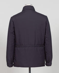 A dark navy blue quilted jacket displayed on a white mannequin torso against a neutral light gray The Gran Sasso Padded Nylon Jacket in navy delivers genuine warmth without the weight. Its lightweight thermowadding construction and refined collar offer understated sophistication—equally at home over a dress shirt or layered with knitwear. Italian craftsmanship meets everyday practicality: polished for client meetings, reliable for daily wear, and versatile enough to become your most trusted layerbackground.