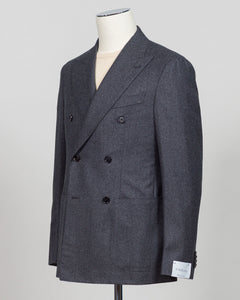 A dark gray double-breasted blazer with a subtle herringbone pattern, displayed on a cream mannequin torso against a light gray background. Refined elegance in a timeless double-breasted silhouette. This Caruso suit pairs the warmth of quality flannel with sophisticated tailoring, delivering understated luxury suited to both boardroom and evening occasions. Dark grey ensures versatility across your wardrobe while the construction speaks to meticulous craftsmanship and enduring style.Caruso Double-Breasted F