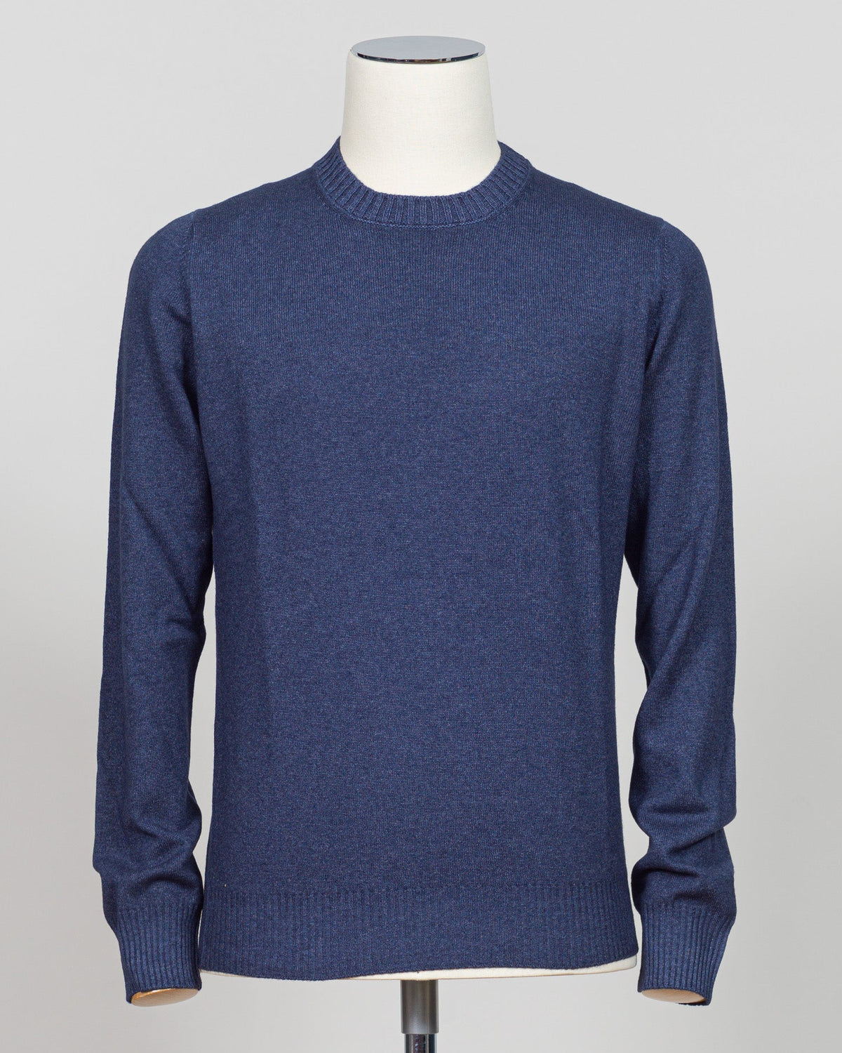 A navy blue long-sleeve knit sweater displayed on a white mannequin torso against a light gray studio background. Italian craftsmanship meets timeless elegance in this Gran Sasso vintage crewneck. Constructed from premium yarns with meticulous attention to detail, this navy essential delivers versatile sophistication for refined wardrobes. The classic crew silhouette and refined knit construction ensure enduring style and comfort across seasons. A foundation piece worthy of investment. Gran sasso blue