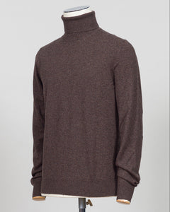 A dark brown knit turtleneck sweater displayed on a mannequin torso against a light gray studio background. Italian craftsmanship meets understated elegance. This Gran Sasso cashmere roll neck in oat delivers refined warmth through premium fibers and meticulous construction. A versatile layering piece that anchors both formal and relaxed wardrobes with timeless appeal. Gran Sasso Cashmere Roll Neck / Dark Brown