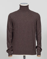 A dark brown knit turtleneck sweater displayed on a mannequin torso against a light gray background. Italian craftsmanship meets understated elegance. This Gran Sasso cashmere roll neck in oat delivers refined warmth through premium fibers and meticulous construction. A versatile layering piece that anchors both formal and relaxed wardrobes with timeless appeal. Gran Sasso Cashmere Roll Neck / Dark Brown