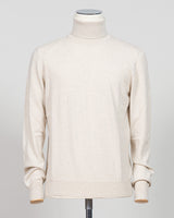 A cream-colored knit turtleneck sweater displayed on a mannequin torso against a light gray studio background. Gran Sasso. Made in Italy.