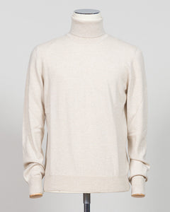 A cream-colored knit turtleneck sweater displayed on a mannequin torso against a light gray studio background. Gran Sasso. Made in Italy.