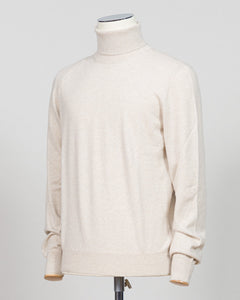 A cream-colored knit turtleneck sweater displayed on a mannequin torso against a light gray studio background. Gran Sasso. Made in Italy.
