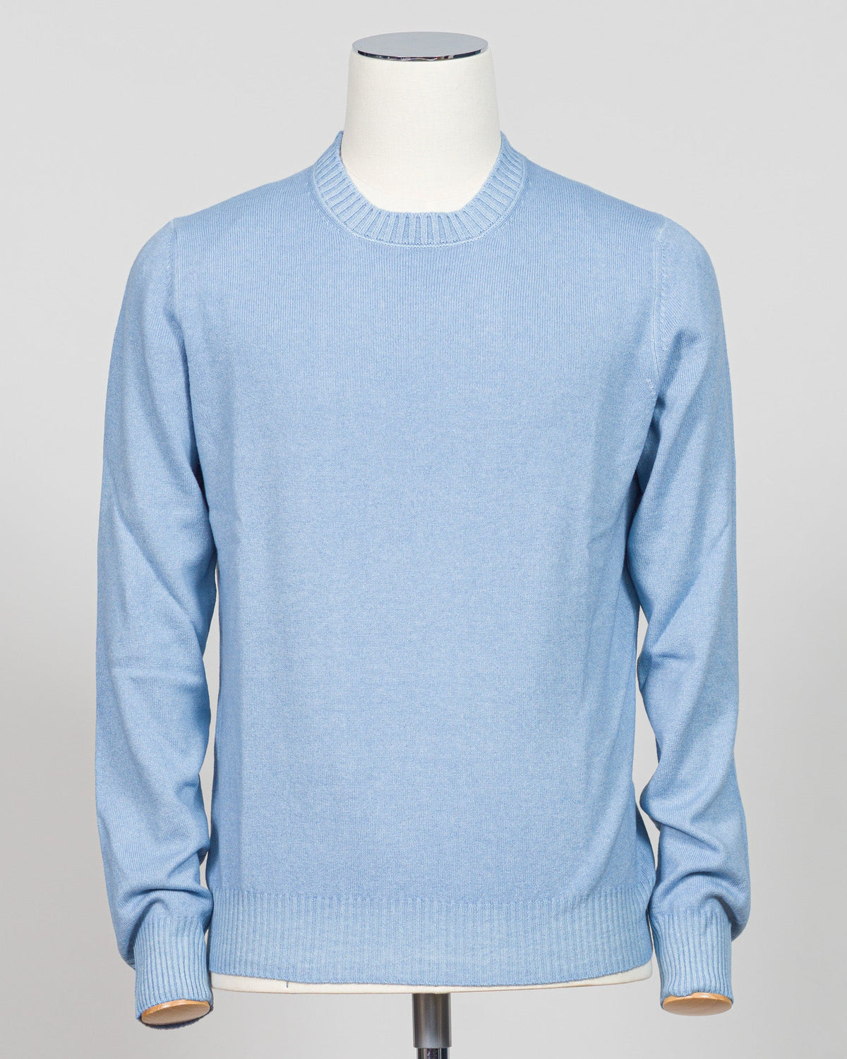 A light blue crewneck knit sweater displayed on a white mannequin torso against a neutral light gray  background. Italian luxury knitwear in a soft light blue. Gran Sasso's refined crewneck delivers timeless sophistication with superior craftsmanship—a versatile layering piece that pairs effortlessly with tailored trousers or casual separates. Premium construction ensures lasting comfort and durability. Gran Sasso Vintage Crewneck / Light Blue