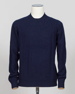 A dark navy blue knit sweater displayed on a white mannequin torso against a light gray studio background. Italian craftsmanship meets luxurious comfort in this Gran Sasso felted cashmere crewneck. The substantial weight and refined texture of premium cashmere deliver warmth without bulk, while the timeless silver tone pairs effortlessly with tailored trousers or structured outerwear.  A foundational piece for the wardrobe—versatile enough for layering, refined enough to stand alone. Gran Sasso Felted Cashm