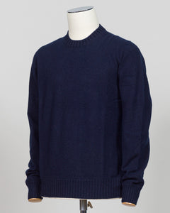 A dark navy blue knit sweater displayed on a white mannequin torso against a light gray studio background. Italian craftsmanship meets luxurious comfort in this Gran Sasso felted cashmere crewneck. The substantial weight and refined texture of premium cashmere deliver warmth without bulk, while the timeless silver tone pairs effortlessly with tailored trousers or structured outerwear.  A foundational piece for the wardrobe—versatile enough for layering, refined enough to stand alone. Gran Sasso Felted Cashm
