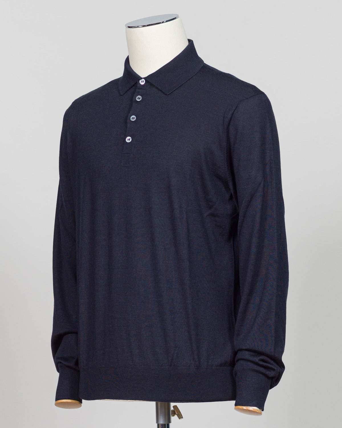 A dark navy blue long-sleeve polo shirt displayed on a white mannequin torso against a light gray background.  Italian craftsmanship meets refined versatility. This Gran Sasso polo blends wool, cashmere, and silk for a lightweight, luxurious knit that transitions effortlessly from casual to elevated dressing. The navy colorway pairs with virtually any tailoring. Premium construction and natural fiber content ensure durability and comfort across seasons. Gran Sasso Wool Cashmere & Silk Polo / Navy
