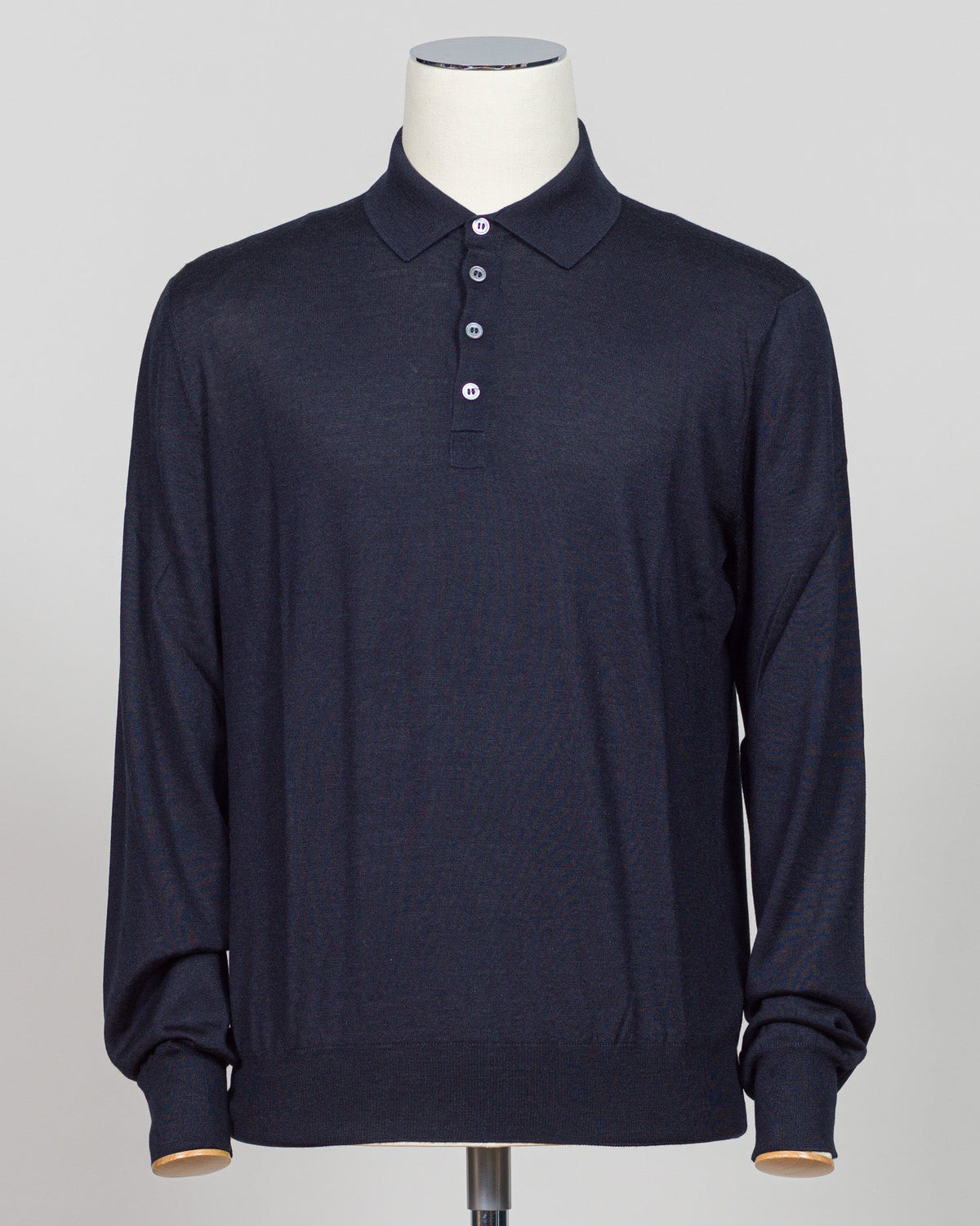 A dark navy blue long-sleeve polo shirt displayed on a white mannequin torso against a light gray background.  Italian craftsmanship meets refined versatility. This Gran Sasso polo blends wool, cashmere, and silk for a lightweight, luxurious knit that transitions effortlessly from casual to elevated dressing. The navy colorway pairs with virtually any tailoring. Premium construction and natural fiber content ensure durability and comfort across seasons. Gran Sasso Wool Cashmere & Silk Polo / Navy