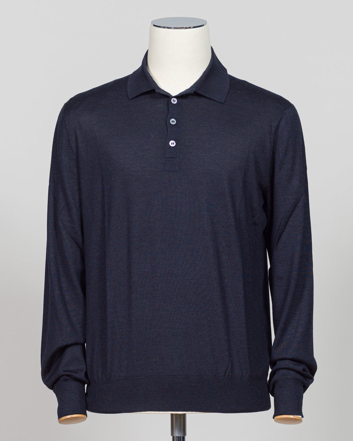 A dark navy blue long-sleeve polo shirt displayed on a white mannequin torso against a light gray background.  Italian craftsmanship meets refined versatility. This Gran Sasso polo blends wool, cashmere, and silk for a lightweight, luxurious knit that transitions effortlessly from casual to elevated dressing. The navy colorway pairs with virtually any tailoring. Premium construction and natural fiber content ensure durability and comfort across seasons. Gran Sasso Wool Cashmere & Silk Polo / Navy