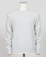A light gray heathered knit crewneck sweater displayed on a white mannequin torso against a neutral light gray background. Italian craftsmanship meets luxurious comfort in this Gran Sasso felted cashmere crewneck. The substantial weight and refined texture of premium cashmere deliver warmth without bulk, while the timeless silver tone pairs effortlessly with tailored trousers or structured outerwear. A foundational piece for the discerning wardrobe—versatile enough for layering, refined enough to stand alon