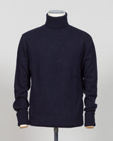 Crafted from premium Italian yarn, the G.R.P. Firenze rollneck knit delivers refined simplicity with architectural precision. The navy tone pairs seamlessly with tailored pieces, while the structured rollneck and clean finish reflect the meticulous construction standards of contemporary menswear. Ideal for layering or worn as a statement piece, this knit bridges casual elegance with wardrobing versatility.