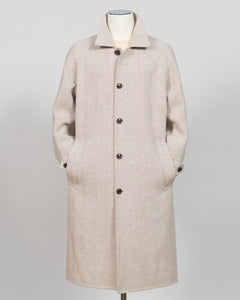 A light beige textured wool-blend coat with a collar, front buttons, and side pockets, displayed on a mannequin against a neutral gray background.