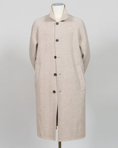 A light beige textured wool coat with a high stand collar and dark buttons, displayed on a mannequin against a neutral gray background.