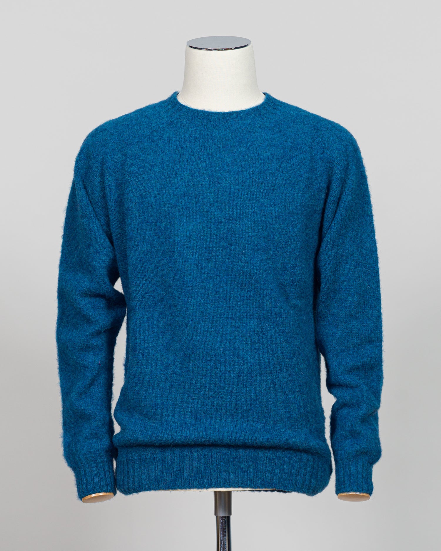 Harley of Scotland's iconic shaggy crew neck sweater in neptune. Hand-knitted using traditional Scottish techniques, this piece features a distinctive textured surface that catches light beautifully while delivering exceptional softness against the skin. The relaxed crew neck silhouette works seamlessly as a standalone layer or under tailored blazers for refined versatility.

Premium wool construction provides natural warmth and breathability across seasons. The generous shag pile creates visual depth and t