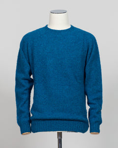 Harley of Scotland's iconic shaggy crew neck sweater in neptune. Hand-knitted using traditional Scottish techniques, this piece features a distinctive textured surface that catches light beautifully while delivering exceptional softness against the skin. The relaxed crew neck silhouette works seamlessly as a standalone layer or under tailored blazers for refined versatility.

Premium wool construction provides natural warmth and breathability across seasons. The generous shag pile creates visual depth and t