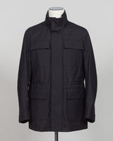 A black utility jacket with a high stand-up collar, displayed on a white mannequin torso against a neutral gray background.