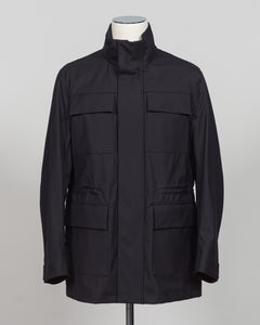 A black utility jacket with a high stand-up collar, displayed on a white mannequin torso against a neutral gray background.